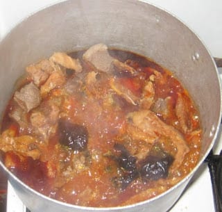 Palm oil and meats boiling in a pot